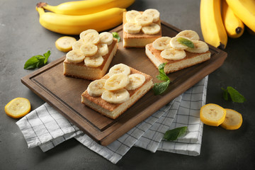Wooden board with pieces of tasty banana cake on table