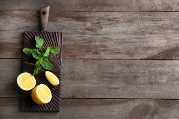 Cutting board with mint and lemon on wooden background