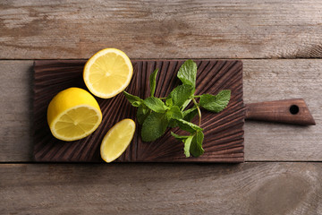 Fototapeta na wymiar Cutting board with mint and lemon on wooden background