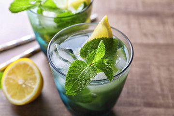 Glass of cocktail with lemon and mint on wooden background