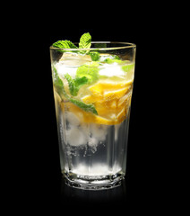 Glass of cocktail with mint and lemon on black background