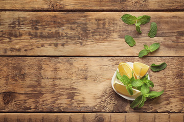 Plate with mint and lemon on wooden background
