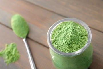 Wheat grass powder in glass jar on blurred background