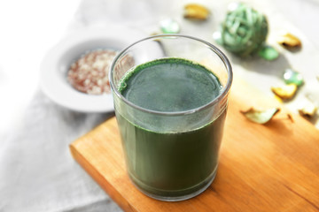 Glass with spirulina drink on wooden board