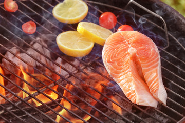 Salmon steak with lemon on barbecue grill, close up