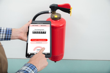 Technician Using Digital Tablet To Check Fire Extinguisher