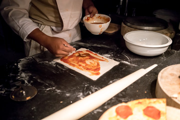 Chef hands making and preparing pizza in a kitchen