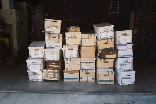 Stacked cardboard boxes filled with of documents sitting in a garage.