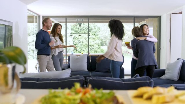 Cheerful group of friends socializing together with drinks in modern home