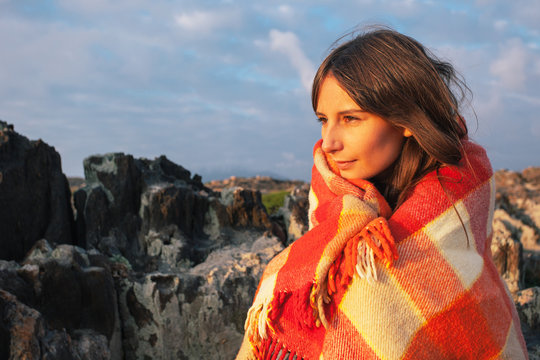 Young Woman Wrapped With Plaid Blanket On Beautiful Landscape.