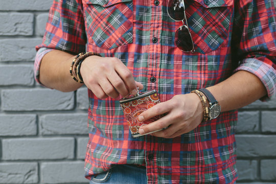 Young man opening a hip flask