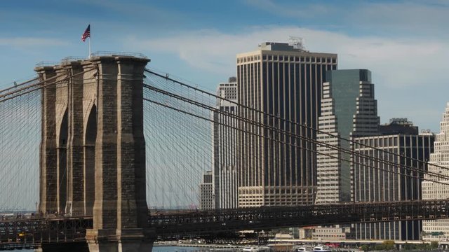 A long shot view of the famous Brooklyn Bridge over the East River with the financial district skyline in the distance.  	
