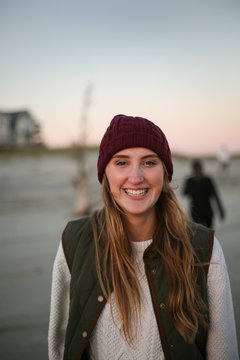 Beautiful young woman outside with hat smiling and looking at camera
