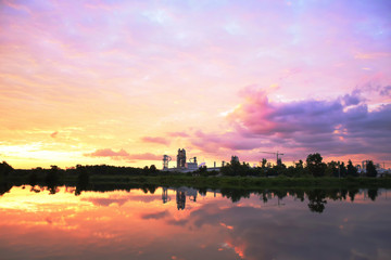 colorful sky and reflection looklike water color painted and silhouette factory in wild forest