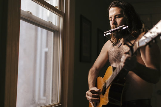 A soulful scruffy musician plays instruments in his Brooklyn Apartment