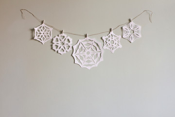 Paper snowflake cutouts hanging from string on wall