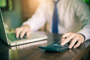 Young businessman using a phone and calculator in his office , and economic analysis