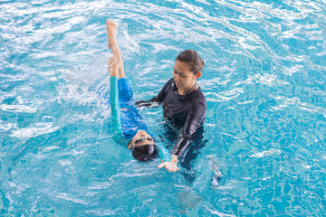 Girl learning to swim with coach at the leisure center