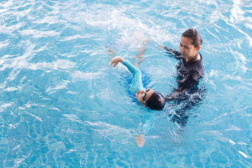 Girl learning to swim with coach at the leisure center