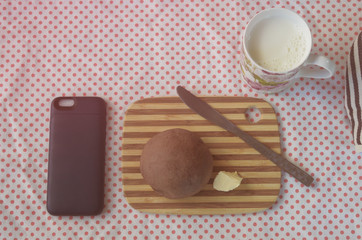 smart phone and chocolate bun with milk on pink polka dot cloth, filtered tones