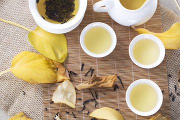 Top view of white tea cups and autumn leaves on the table. Autumn tea.