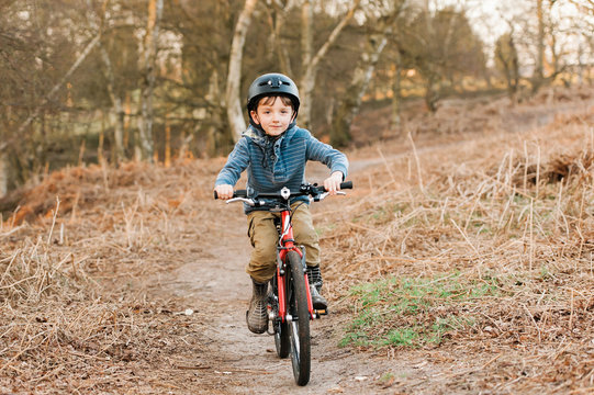 Zoom!  Smiling boy cycles down hill towards camera.