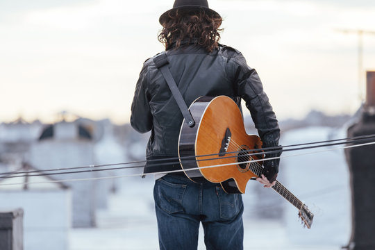 Young musician has guitar on rooftop
