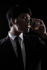 portrait of Asian man in black formal suit with a glass of whisky