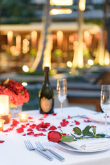 Special romantic candle light dinner table set up by the pool for couple with a bottle of champaign