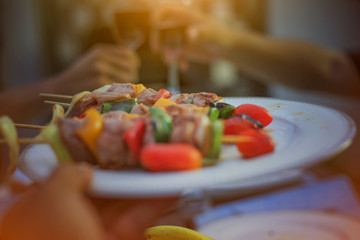 The waitress holds a plate with a barbecue. Behind the picture is the celebration of the new year and the blur.