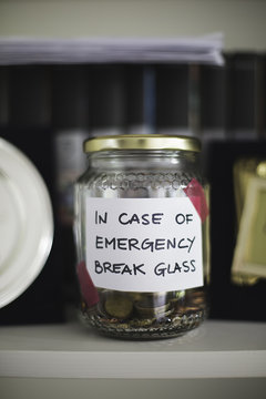 Money saving in jar with label saying 'in case of emergency break glass'