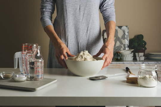 woman ready to prepare the dough, facing the bowl of flour, work table.