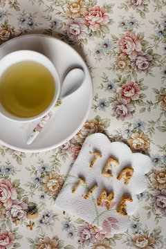 Overhead image of tea time biscuits on a napkin and a cup of tea
