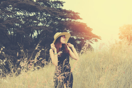 Female tourist wearing a hat standing on an outdoor lawn. She breathes fresh air for her vacations. happy holiday