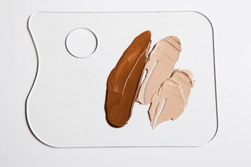 Cosmetic foundation different shades swatch on palette on white background, close up. Professional make up product for face and concealer samples