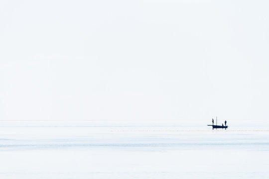 Silhouette of a boat and fishermen on calm sea