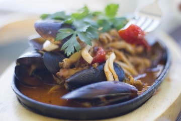 Hand holding a fork and a mussel; restaurant setting