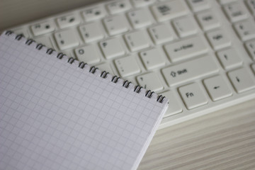 white keyboard and notebook on the white table. business concept
