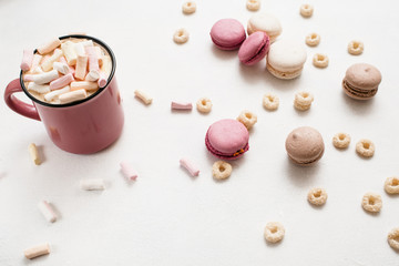 Delicious latte with macaroons on white table. Hot drink with marshmallow and colorful sweets around top view