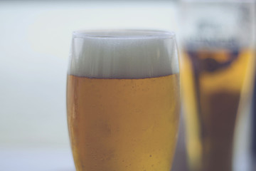 Two glasses of beers on a wooden table.