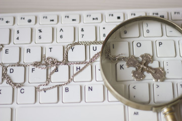 silver chain with a cross lying on a white keyboard