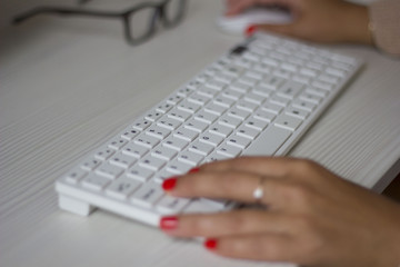 Female hands typing on white computer keyboard