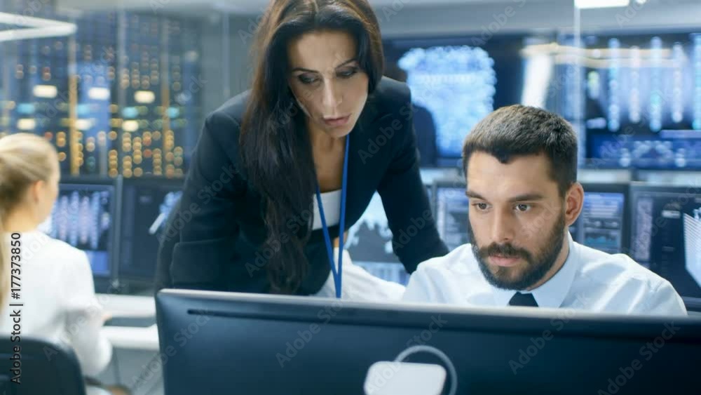 Poster Female Chief Computer Engineer Consults Male Neural Network Architect. They Work in a Crowded Office on a Neural Network.