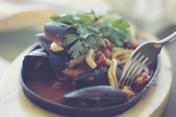 Hand holding a fork and a mussel; restaurant setting