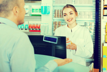 Fototapeta premium Smiling female pharmacist counseling customer about drugs usage