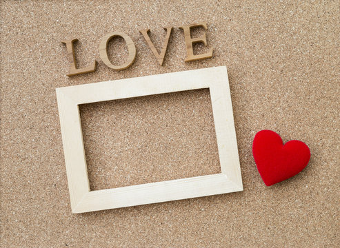 Love wooden text and wooden frame with red heart on corkboard texture