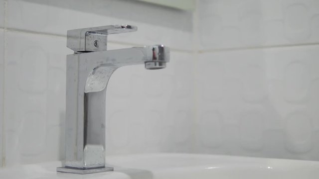 4K: Female hands washing under running water in a sink. Turning on tap, close up of adult hand turning on water and turning it off