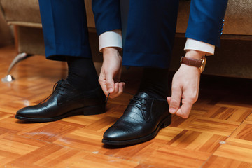 Groom's morning. Wedding accessories. Shoes. The groom ties the shoelaces on his shoes