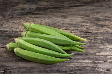 pile of raw okra on old and crack wooden surface background. organic healthy food concept.
