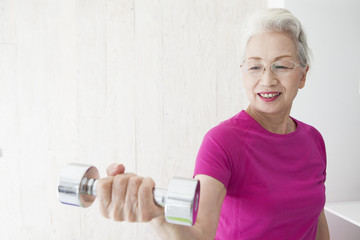 An old woman is training her arm with a dumbbell